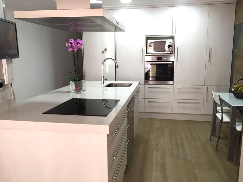 Cocina moderna blanca con isla central y placa de inducción